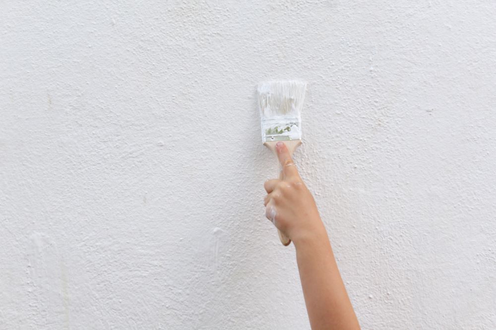 Applying multiple coats of paint to a stucco surface during stucco painting.